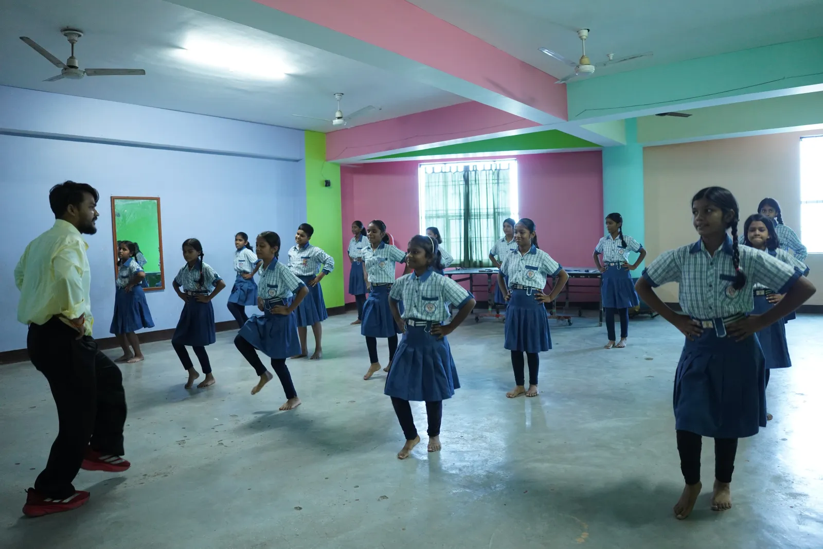 A dance teacher leading a class of girls in the activity room