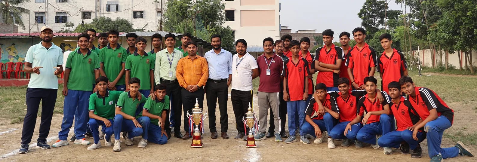 The finalists of the Inter-House Cricket Championship in their green and red house kits, with teachers and trophies on the school field