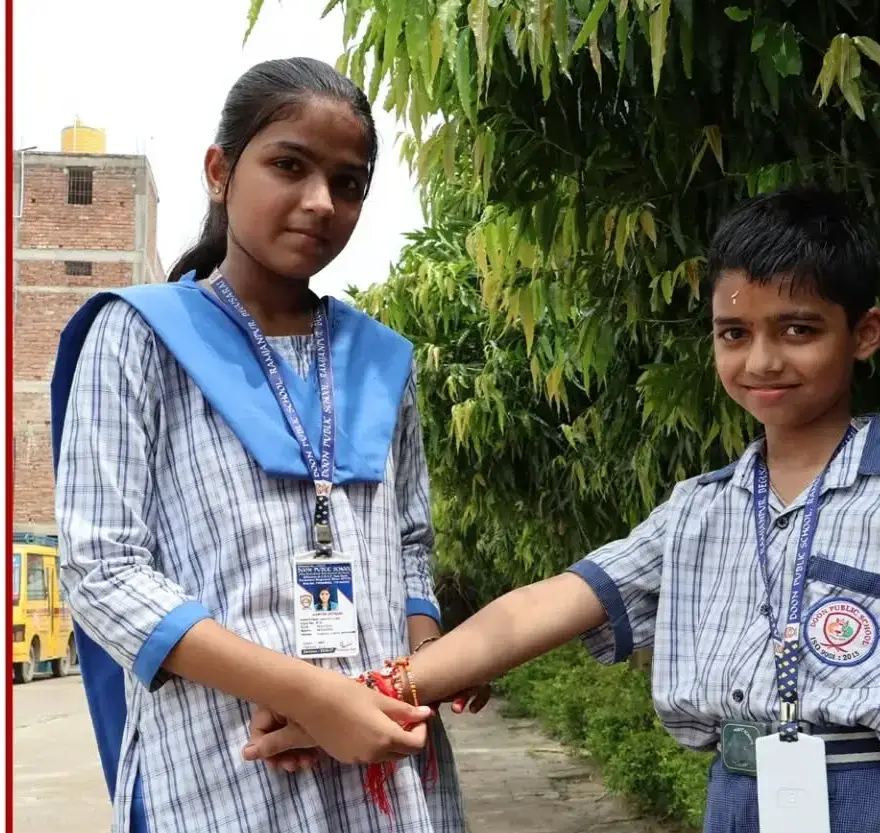 A student tying a rakhi on a younger schoolmate's wrist