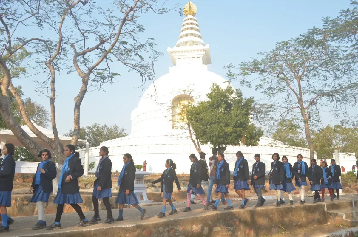 Students walking past a white stupa on an educational trip